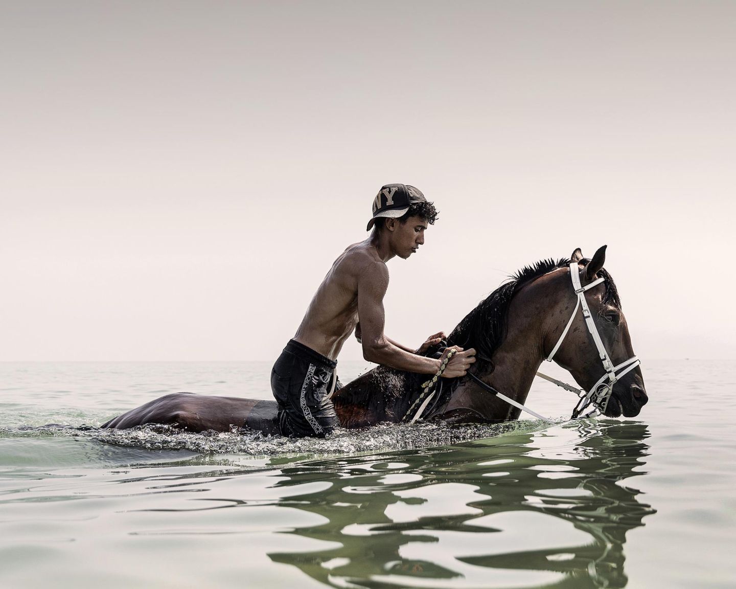 Junge reitet auf einem Pferd im Wasser