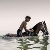 Junge reitet auf einem Pferd im Wasser