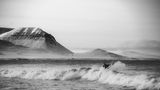 Surfer in Island vor einer Bergkulisse