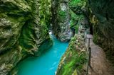 In der Schlucht, ein schmaler Wanderweg unter Felsen, auf denen Moos wächst.