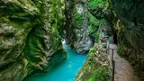 In der Schlucht, ein schmaler Wanderweg unter Felsen, auf denen Moos wächst.