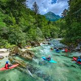 Kajakfahrer schweben auf dem Wildwasser, Bäume, hinten ein Berg