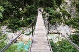 Hängebrücke über Fluss und Felsen mit Fahrradfahrer