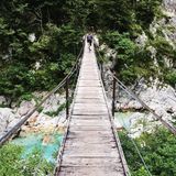 Hängebrücke über Fluss und Felsen mit Fahrradfahrer