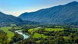 Breites Tal mit Fluss und Bergen im Hintergrund