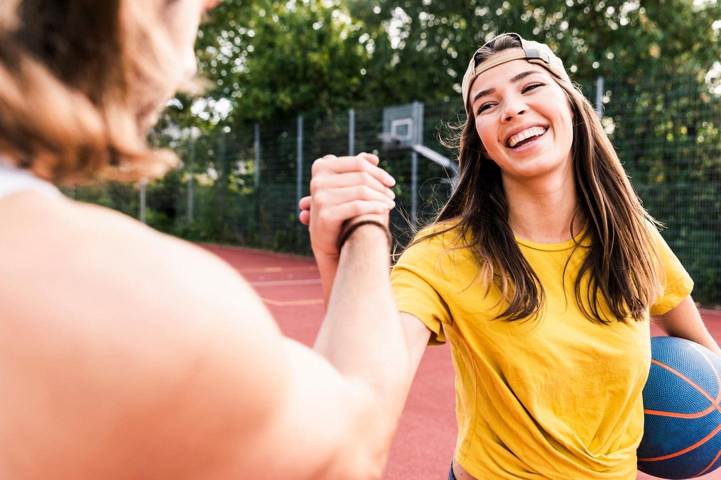 Frau mit Basketball unterm Arm schlägt ein