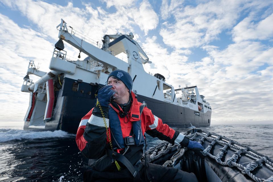 Mann im  Beiboot auf dem Meer. Grosses Schiff im Hintergrund  1.5026