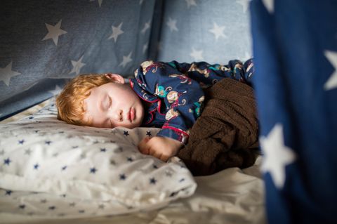 Circa 3- 5 jähriger rothaariger Junge schläft auf einem Kopfkissen im Spieltippi.