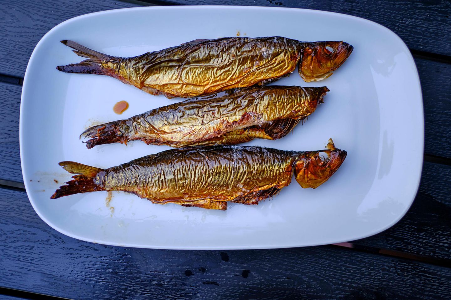 Hering, Wein und Feigen Drei servierfertige Fische auf einem Teller