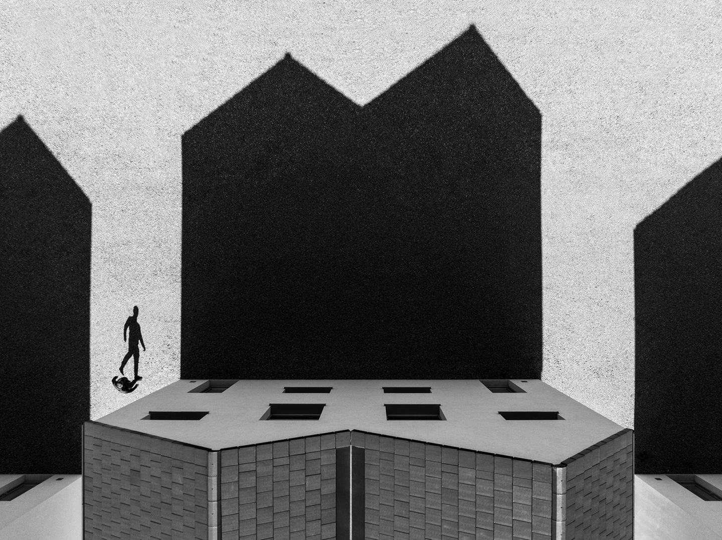 Am Rande Schlesiens im Süden Polens kehrt ein Bewohner in sein Zuhause zurück. Das Bild zeigt dagegen nur ein verzerrtes Abbild, die Schatten von Haus und Mensch auf den Boden werfen und dort vom Fotografen Jeremiasz Gadek eingefangen wurden