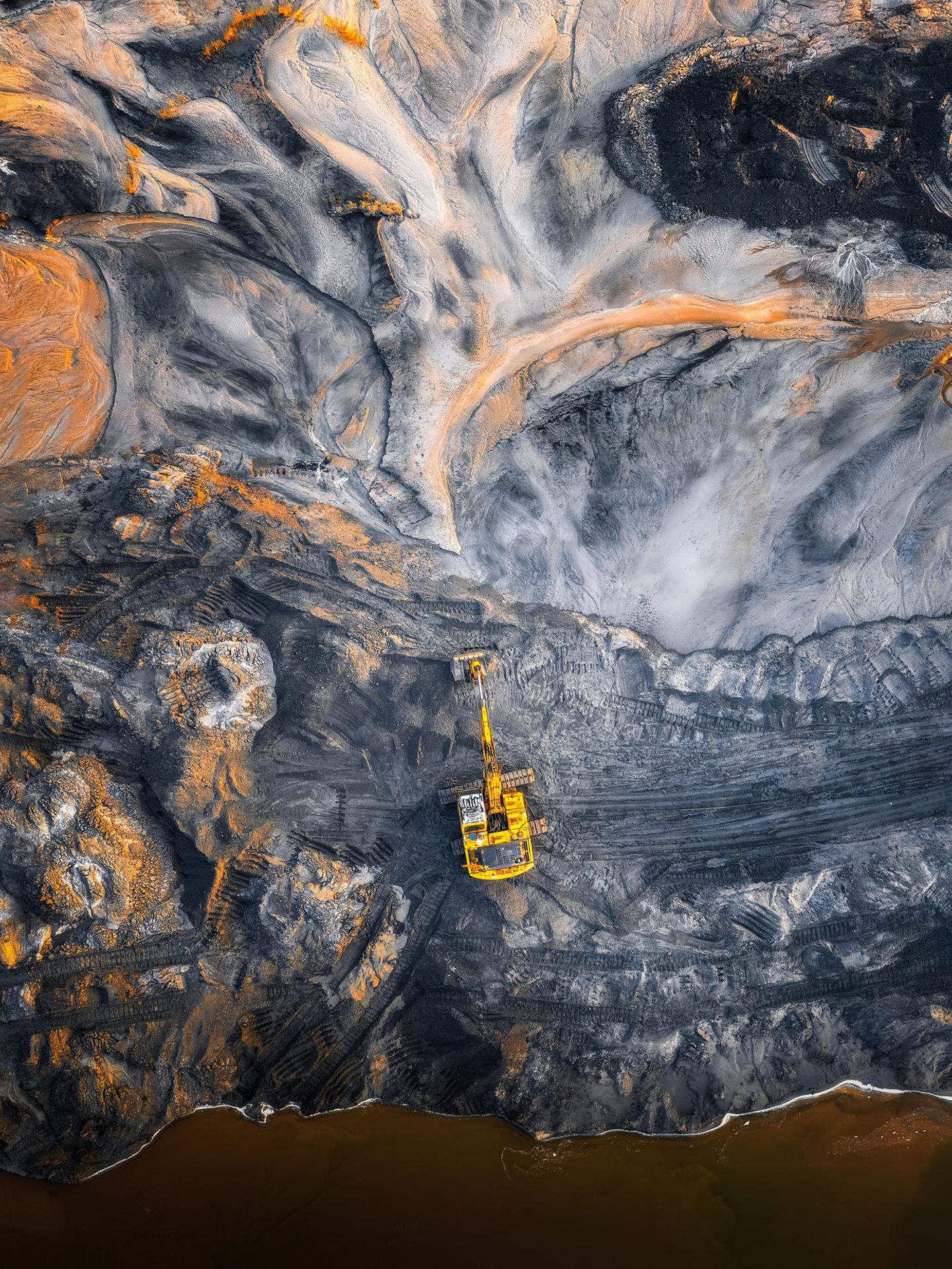 Orangefarbenes Licht trifft auf ein Bergbaugebiet der Stadt Ningbo in China. Die Aufnahme der Fotografin Xuhana zeigt die Formen, die der Mensch in der Natur hinterlässt – auf der Suche nach Rohstoffen