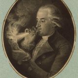 Ein Mann bläst durch ein dünnes Rohr Wasserstoff in eine Flamme, die heftig auflodert