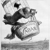 Eine Karikatur zeigt einen Mann in einer Ballongondel, der einen großen Fotoapparat hält und dessen Hut wegfliegt