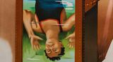 Ein buntes, gemaltes Reklame-Plakat zeigt Houdini kopfüber in einem Wassertank