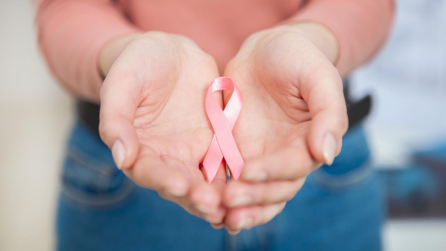 Rosa Schleife in den Händen einer Frau