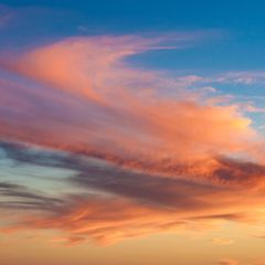 Himmel mit langgezogenen, vom Sonnenlicht rot-orange gefärbten Wolken