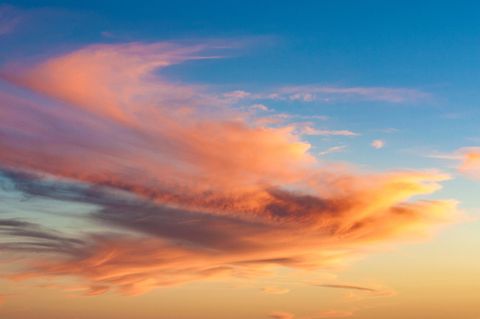 Himmel mit langgezogenen, vom Sonnenlicht rot-orange gefärbten Wolken