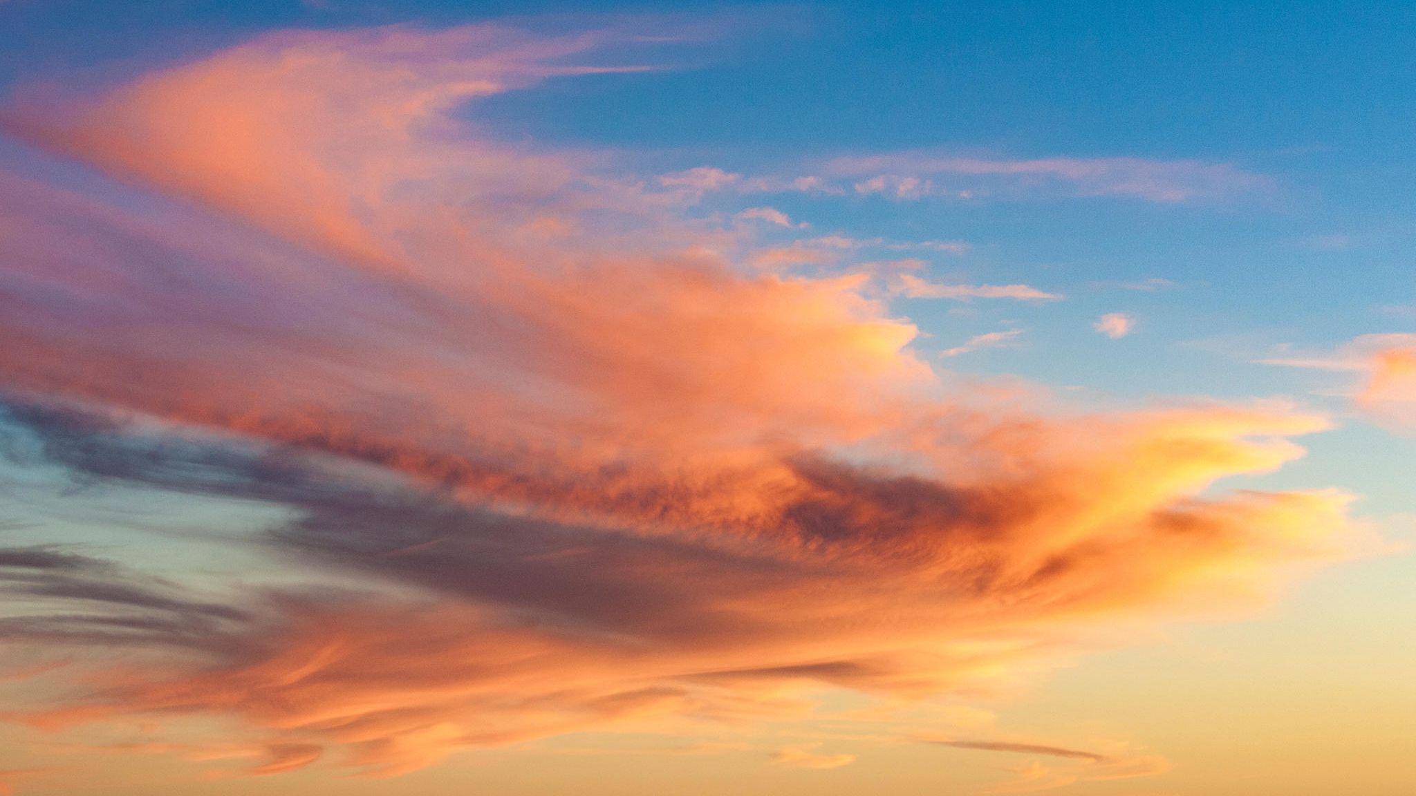 Himmel mit langgezogenen, vom Sonnenlicht rot-orange gefärbten Wolken