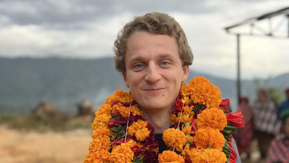 Linus Günther trägt Blumenkränze und strahlt