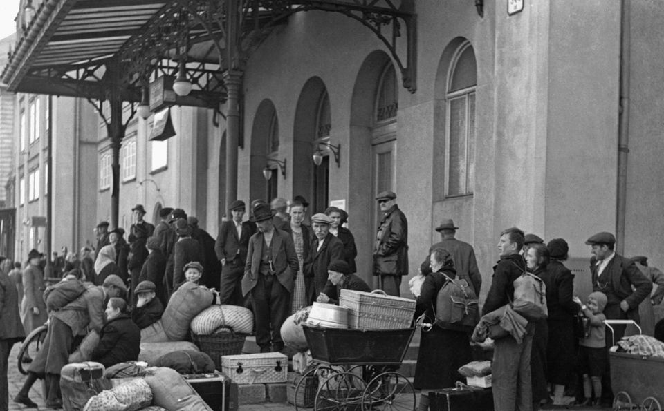 Männer, Frauen und Kinder auf der Flucht warten mit vielen Koffern, Säcken, Körben und Kinderwagen unter einem Bahnhofsvordach Männer, Frauen und Kinder auf der Flucht warten mit vielen Koffern, Säcken, Körben und Kinderwagen unter einem Bahnhofsvordach