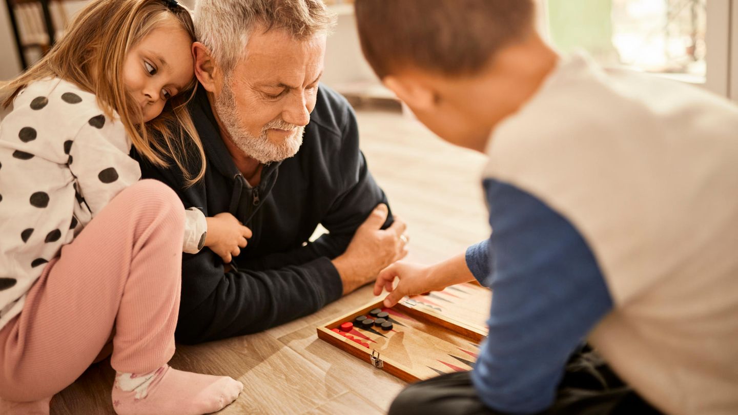 Opa und zwei Kinder spielen Backgammon