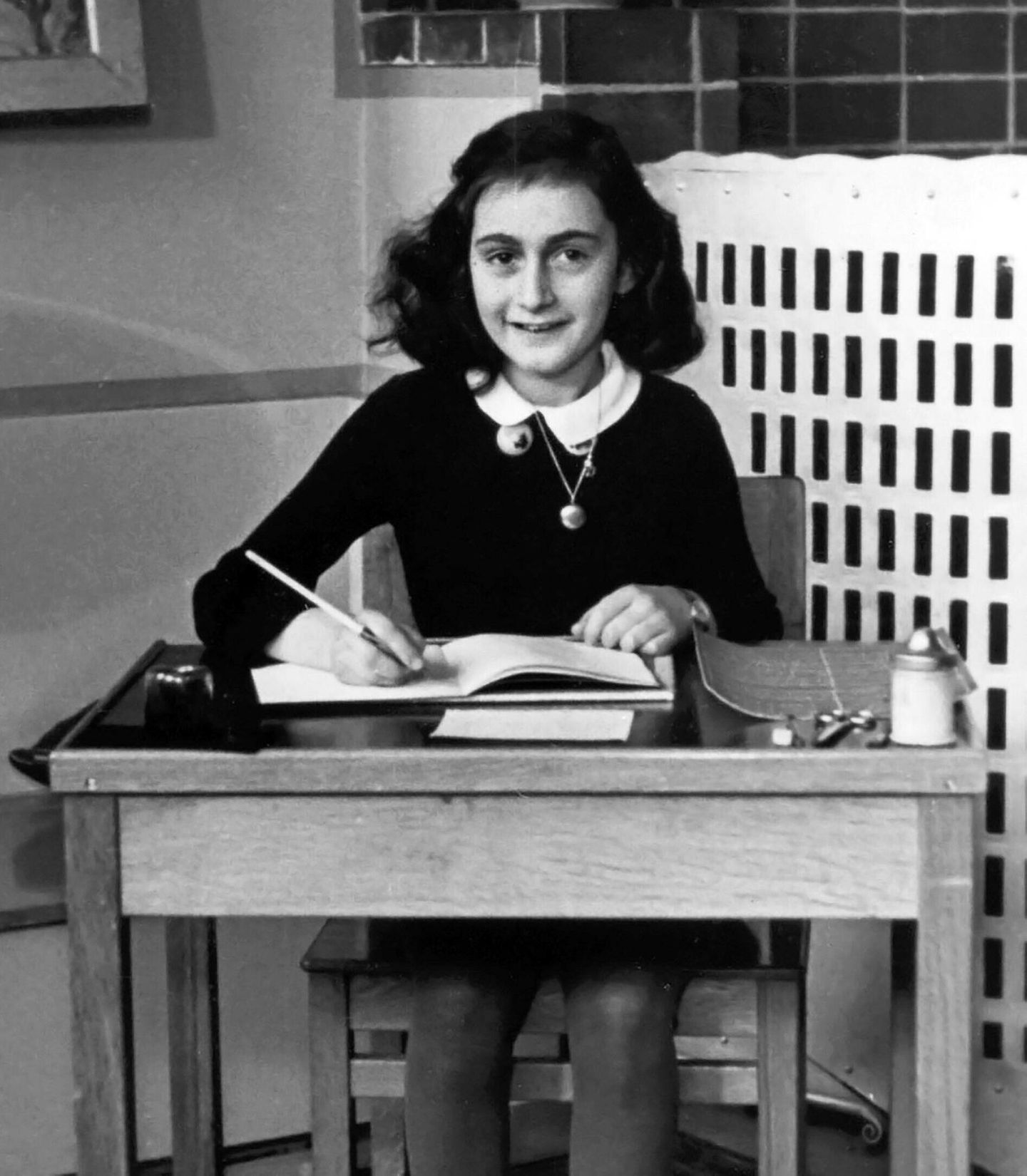 Ein Buch gegen das Vergessen: Anne Frank Anne Frank sitzt an einem Tisch, ein aufgeschlagenes Heft zum Schreiben vor sich