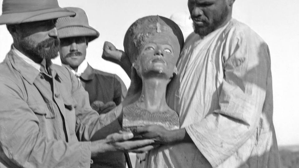 Männer halten die Büste der Nofretete in die Höhe Männer halten die Büste der Nofretete in die Höhe