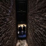 Blick durch einen dunklen Gang, an dessen Ende eine Falltür in der Luft hängt