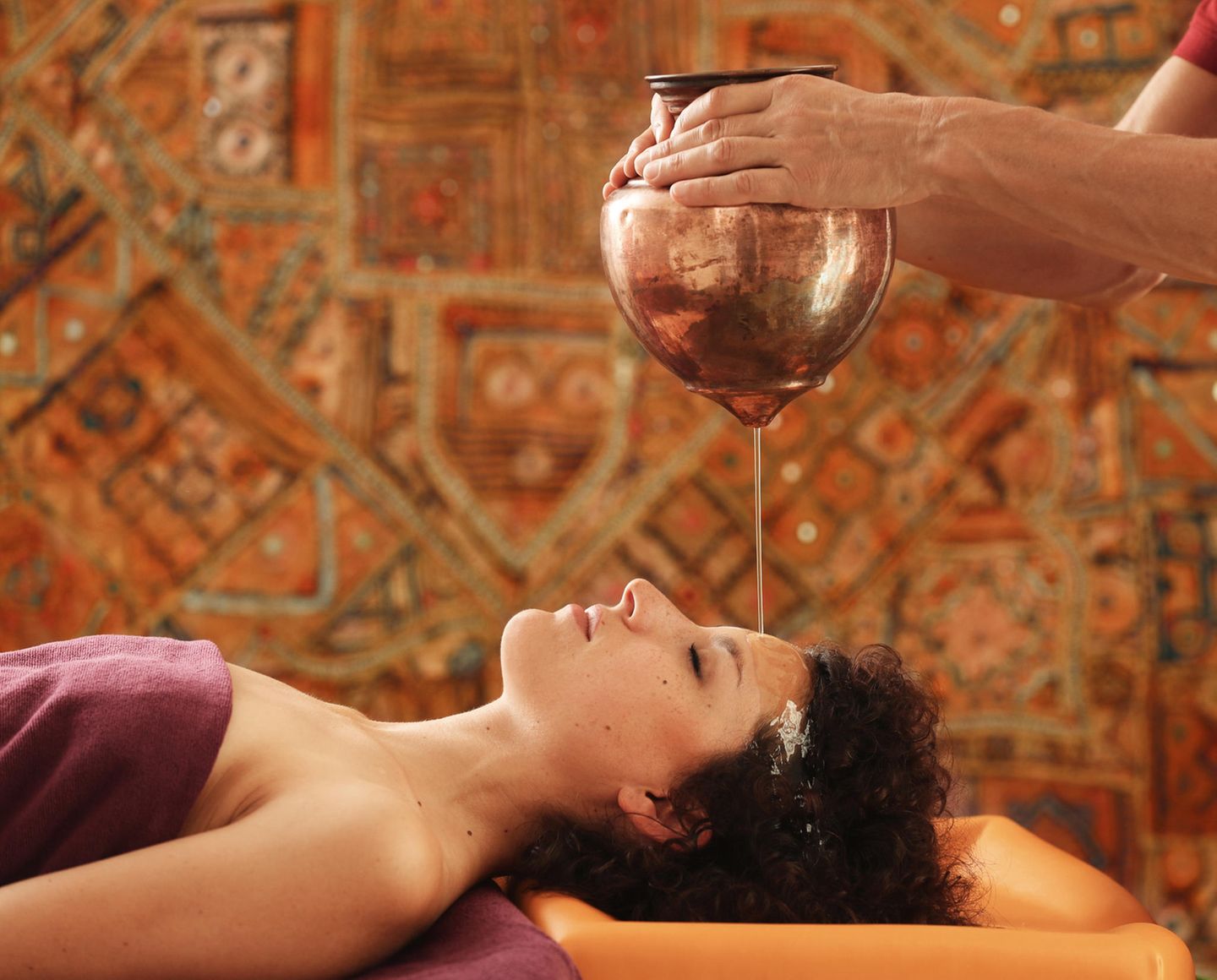 Rosenberg Ayurveda Kurzentrum, Spessart Frau liegt, Öl tropft aus Kupferkessel zum Stirnguss