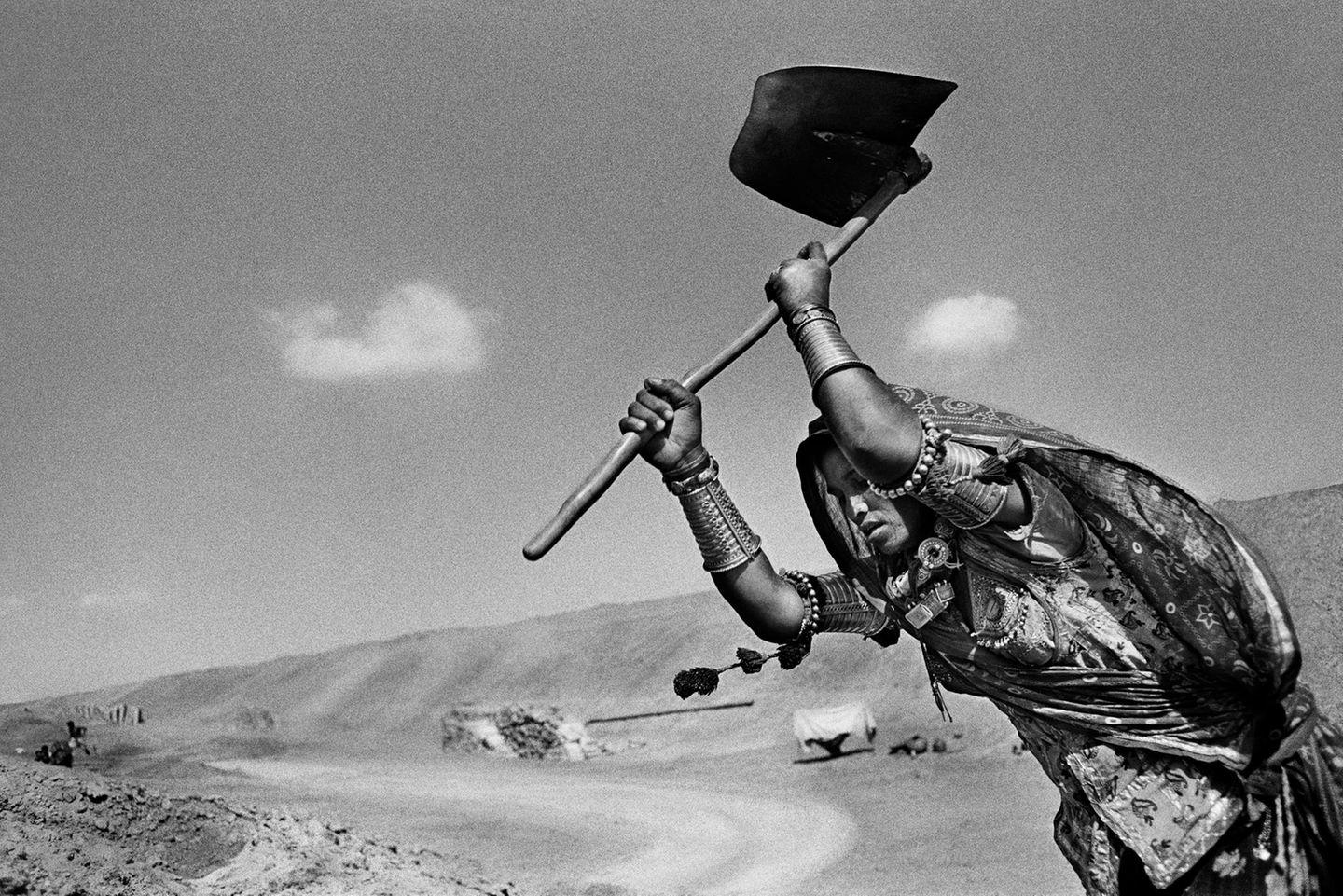 Sebastião Salgado, Brasilianer, geboren 1944, verortet sich in der Tradition der sozialdokumentarischen Fotografie, seine Bilder sind kämpferisch und oft den Vergessenen und Ausgegrenzten gewidmet. In der Serie "Workers" zeigt er Menschen, die hart mit ihren Händen arbeiten, ein unverzichtbarer Teil menschlichen Daseins. Dieses Bild entstand 1989 in Indien und zeigt eine Frau, die mit einer rudimentären Schaufel Gräben für den Indira-Ghandi-Kanal aushebt – für einen Stundenlohn von etwas über einem Dollar. Das gigantische Unternehmen wurde 1958 begonnen, inzwischen ist immerhin der 650 Kilometer lange Hauptkanal fertiggestellt. Die Bauarbeiten bestimmten über Jahrzehnte das Leben vieler Familien in der Grenzregion zu Pakistan, dort sichern die vielen Nebenkanäle auch die Wasserversorgung. Der Kanal gilt in vielen Ländern Afrikas und Südamerikas wegen seiner niedrigen Baukosten und des sozialen Nutzens als Musterprojekt.    