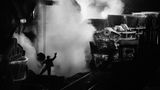 Stahlerzeugung ist eine grundlegende Produktionstechnik. Das Metall ist nicht nur Grundstoff des Transport- und Bauwesens – ohne Stahl würde die komplette Wirtschaft vieler Länder zusammenbrechen. 1987 fotografierte Salgado  im ukrainischen Stahlwerk Saporischschja: Ein Arbeiter überwacht das Ausgießen glühenden Spezialstahls in Transportloren; aus ihm werden später Bleche für die Autoindustrie gewalzt.    