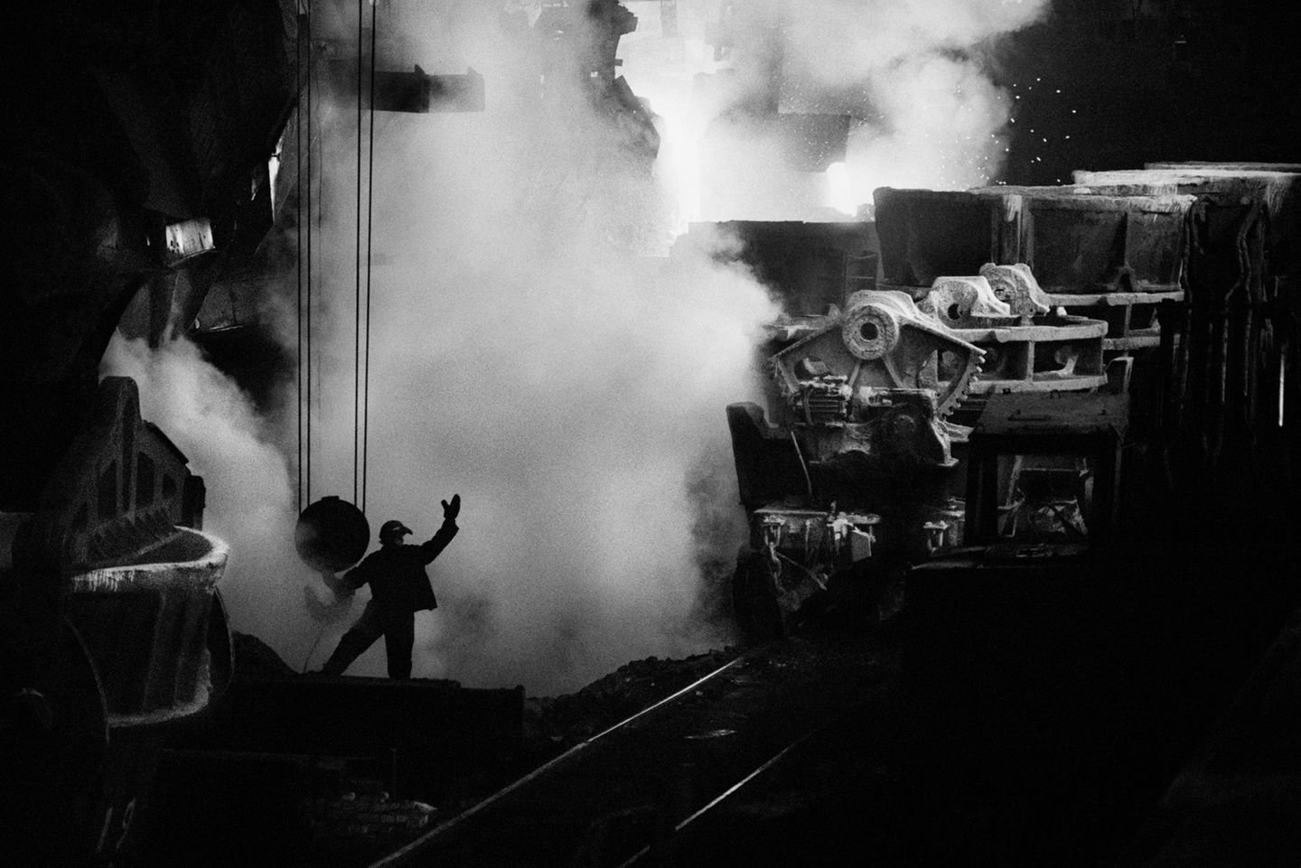 Stahlerzeugung ist eine grundlegende Produktionstechnik. Das Metall ist nicht nur Grundstoff des Transport- und Bauwesens – ohne Stahl würde die komplette Wirtschaft vieler Länder zusammenbrechen. 1987 fotografierte Salgado  im ukrainischen Stahlwerk Saporischschja: Ein Arbeiter überwacht das Ausgießen glühenden Spezialstahls in Transportloren; aus ihm werden später Bleche für die Autoindustrie gewalzt.    