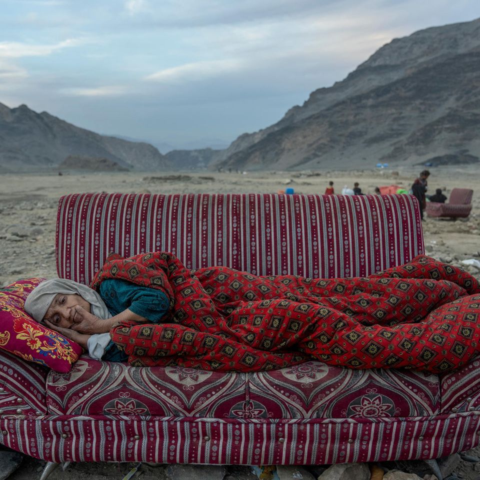 Bett im Freien: Mitten in der Wüste ruht sich eine Afghanin auf einem behelfsmäßigen Schlafplatz aus. In der Nähe liegt ein Lager, in dem kürzlich aus Pakistan abgeschobene Menschen untergebracht sind, nahe der pakistanisch-afghanischen Grenze. Seit die Taliban im August 2021 an die Macht kamen, wird die bereits vom Krieg zerstörte Wirtschaft weiterhin durch den Abzug ausländischer Hilfe beeinträchtigt. Eine vierjährige Dürre und zwei schwere Erdbeben haben die Krise verschärft. Die UN schätzt, dass 97 Prozent der afghanischen Bevölkerung unterhalb der Armutsgrenze leben. Die Zahl der Vertriebenen liegt bei über sechs Millionen.