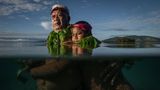 Großvater steht im brusthohen Wasser mit seinem Enkel im Arm