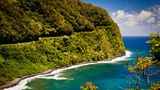 Strasse nach Hana zerschneidet einen bewaldeten Hang, unten ist das Meer