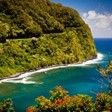 Strasse nach Hana zerschneidet einen bewaldeten Hang, unten ist das Meer