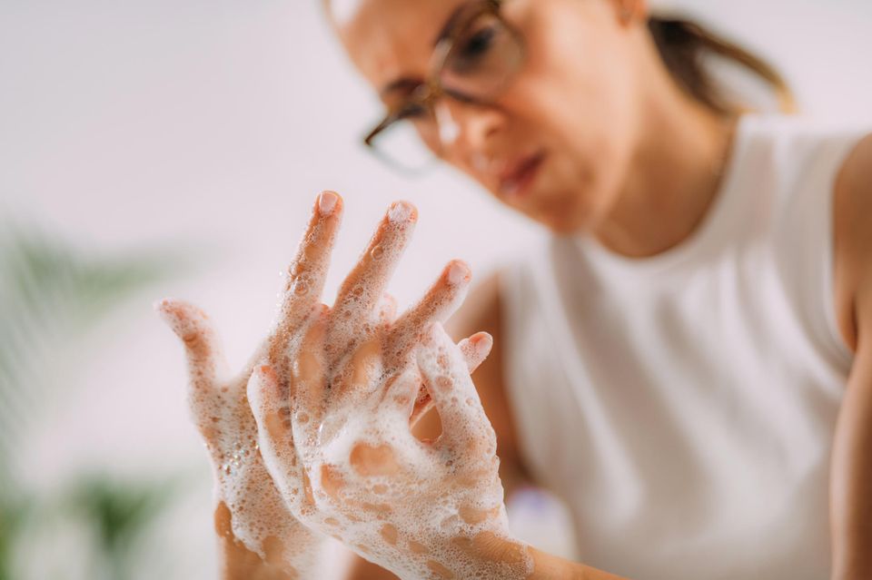 Frau seift sich mit angestrengtem Gesicht die Hände ein  1.5004