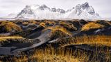 Winter in Stokksnes, Island: Das Bild zeigt einen schwarzen Sandstrand, im Hintergrund liegt der majestätische Berg Vestrahorn. Fotograf Ivan Pedrettie liebt an seinem Bild besonders den Farbkontrast zwischen den weißen Bergen und den schwarzen Dünen, die gelbe Gräser zieren.