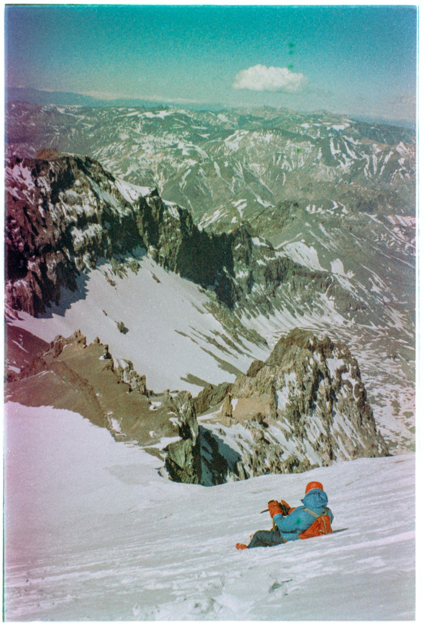 Eine Person liegt im Schnee mit Blick auf Berge