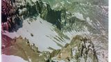 Eine Person liegt im Schnee mit Blick auf Berge