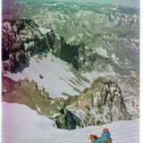 Eine Person liegt im Schnee mit Blick auf Berge