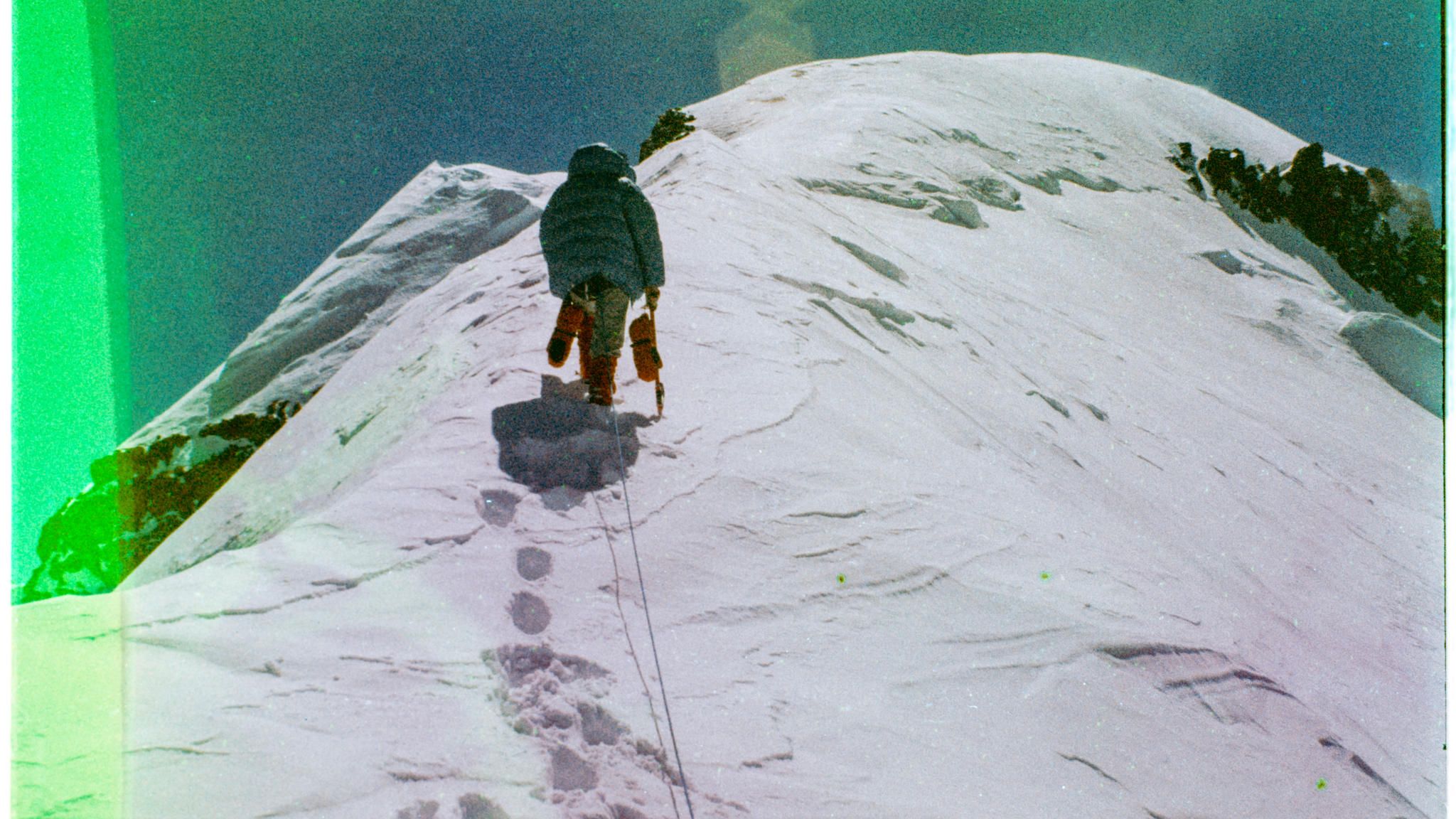 Der Zusammenbruch EIne Person klettert den Berg hoch und hinterlässt dabei Fußabdrücke im Schnee
