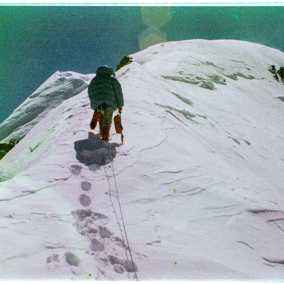 Der Zusammenbruch EIne Person klettert den Berg hoch und hinterlässt dabei Fußabdrücke im Schnee