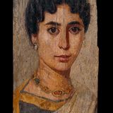 Eine Dame im Dreiviertelprofil mit dunklen Haar, glänzenden Ohrringen und einer Halskette mit Gold und Edelsteinen