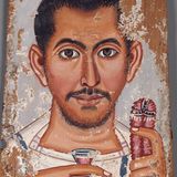 Ein Mann in einer weißen Tunika hält ein kleines Glas mit einer roten Flüssigkeit in der rechten Hand