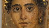 Eine junge Frau mit goldenem Haarkranz und großen Augen mit schlangenförmigen, goldenen Ohrringen