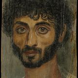 Ein Mann mit dunklen Locken und stark hervorstehenden Wangenknochen