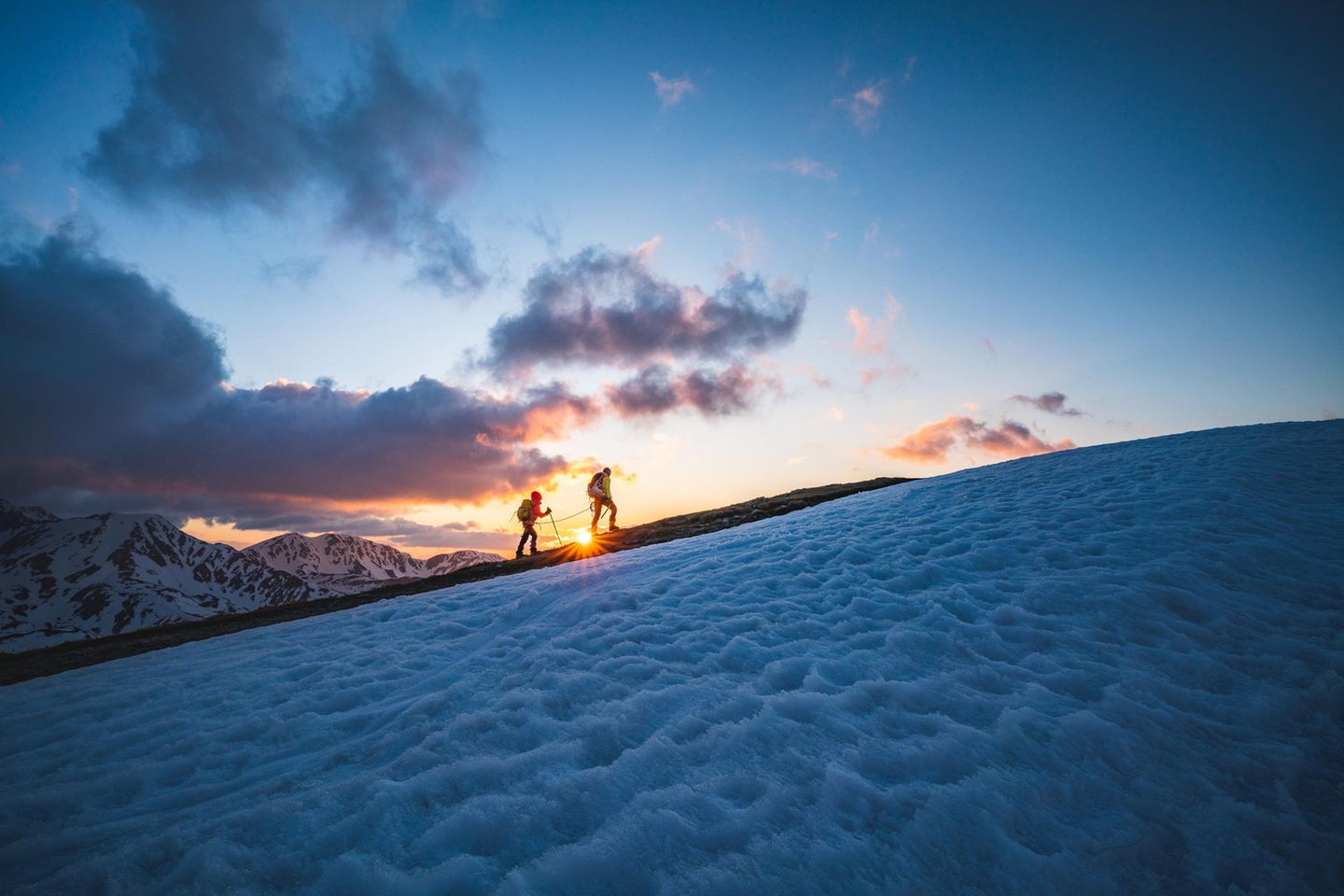 Hohe Tatra – Polen Zwei Leute wandern in der Abenddämmerung ein Gebirge hoch.