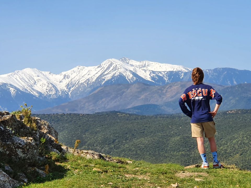 Junge in kurzen Hosen schaut auf verschneiten Berg.