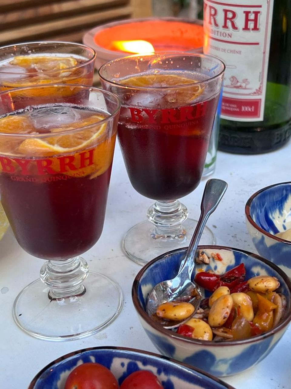 Drei Cocktails und eine Flasche auf einem Tisch.